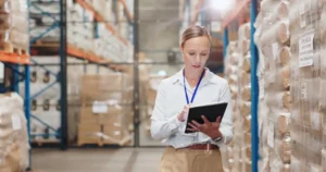 Warehouse manager checking inventory on a tablet between storage racks.