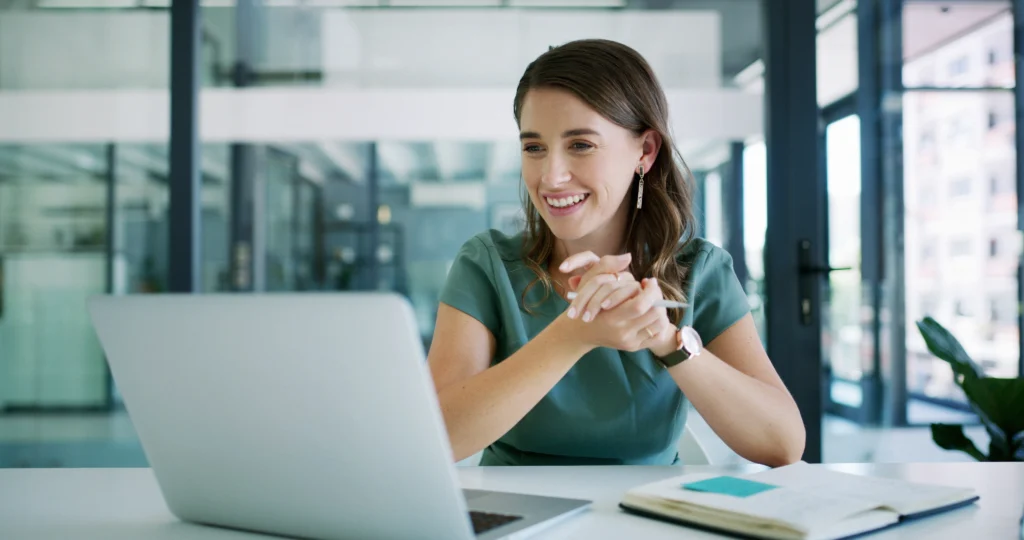 woman at office desk smiling as she participates in an online training